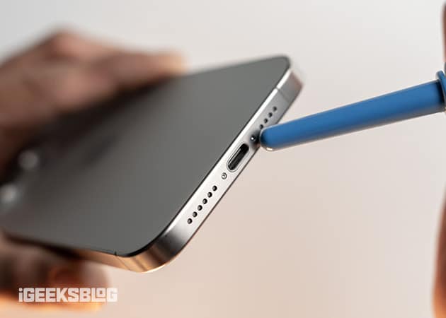 Blowing compressed air into the charging port of an iPhone to clean it.