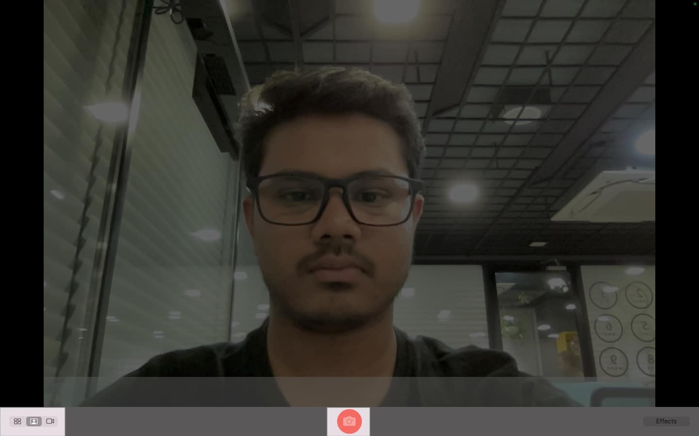 Clicking the shutter button to take a picture in Photo Booth on a Mac.