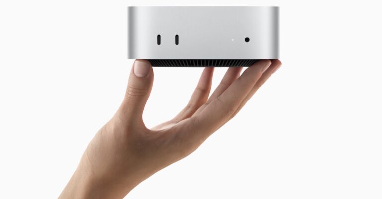Apple Mac mini held in one hand.