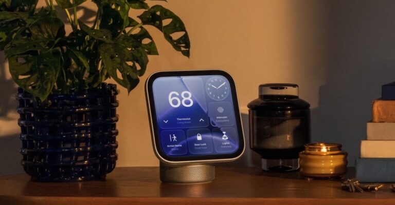 HomeView tabletop display showing thermostat and door lock controls on a wooden sideboard beside a potted plant in a warm-lit living room