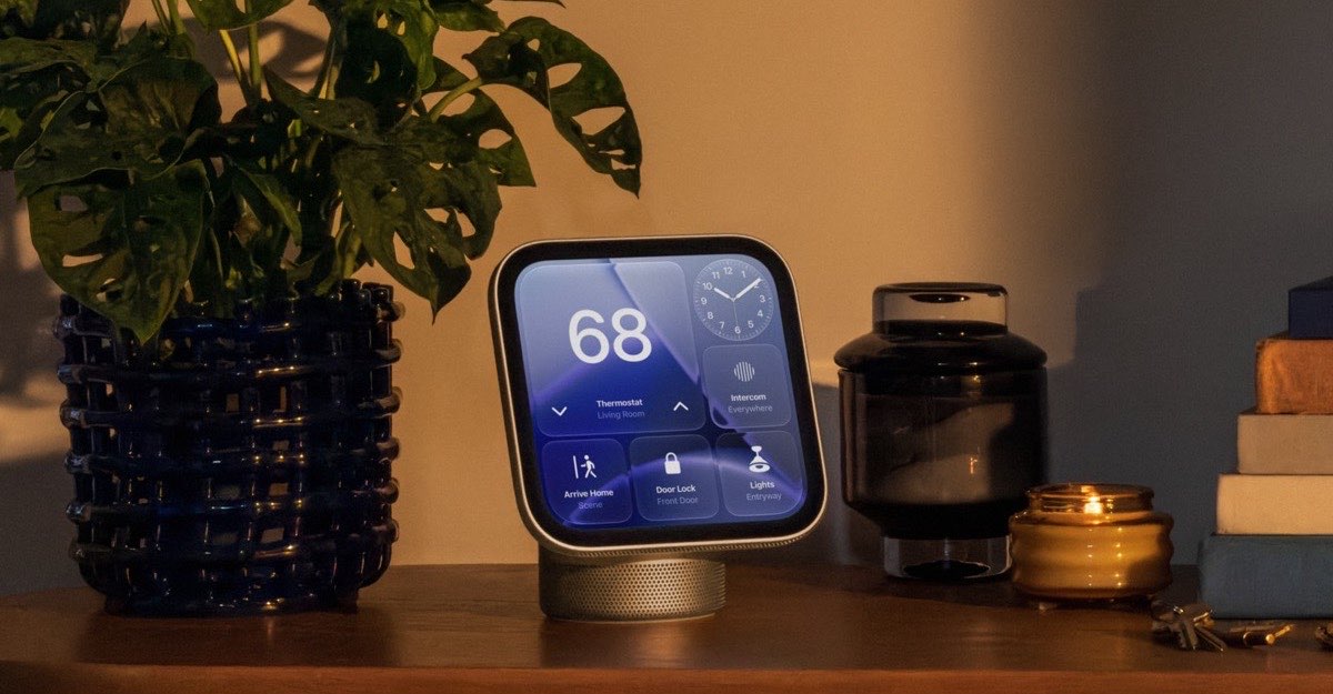 HomeView tabletop display showing thermostat and door lock controls on a wooden sideboard beside a potted plant in a warm-lit living room