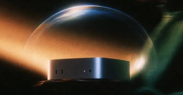 Silver Mac mini in front of a glowing planet-like backdrop on a dark background