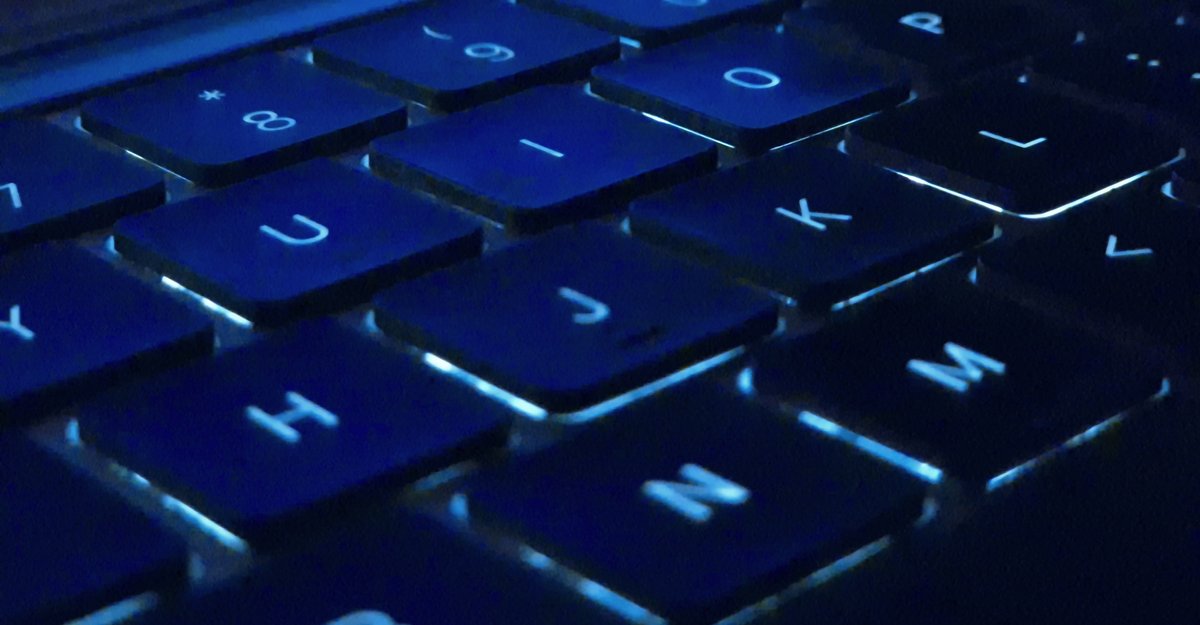 Close-up of backlit MacBook Pro keys glowing blue